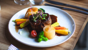 Elegant beef entrée with vegetables, artfully plated by a private chef.