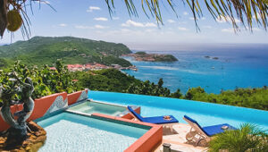 Infinity pool overlooking a lush green hillside and turquoise ocean in Gustavia.