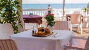Beachfront dining table with gourmet burger and fries at a seaside restaurant in St. Barts.