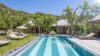 Sunlit swimming pool at Villa Armancaya surrounded by palm trees, tropical gardens, and hillside views in St Barts
