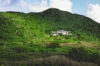 Secluded luxury villa nestled in lush green hills, surrounded by tropical vegetation and mountain scenery under a bright sky