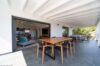 Covered outdoor dining terrace with wooden table and ocean-view lounge at a contemporary St Barts villa rental.