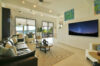 Elegant living room with leather sofas and large TV opening to terrace with sea view at luxury villa in St Barthélemy.