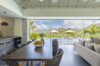 Open kitchen and dining area with pool and hillside view inside luxury villa rental in St Barths