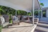 Shaded wooden terrace with lounge seating surrounded by tropical greenery at private villa rental in St Barthélemy.