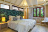 Cozy tropical bedroom with a botanical headboard, soft lighting, and windows overlooking lush greenery