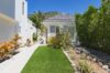Charming white villa surrounded by tropical plants and a manicured lawn under a bright blue sky