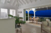 Cozy coastal living area opening to a terrace with a wooden dining set and ocean views under a twilight sky