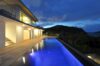 Twilight view of illuminated infinity pool and modern architecture at Villa Plumbago, St Barts luxury rentals.
