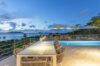 Elegant outdoor dining terrace with illuminated pool and ocean views at a St Barts luxury villa rental.
