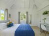 Bright bedroom with vaulted ceilings, blue accents, and garden views at a luxury villa in St Barts