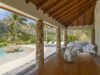 Covered terrace with stone columns overlooking a lagoon-style pool and tropical hills at a private villa rental in St Barts