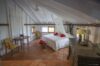 Bright attic bedroom with terracotta floors, white canopy bed, and tropical charm at a St Barts villa rental.