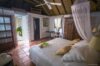 Tropical-style bedroom with canopy bed, wooden furnishings, and garden views at a private villa rental in St Barts.