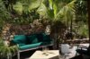 Shaded garden lounge with green cushions and palm trees at a tropical St Barts villa rental.