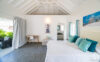 Bright bedroom with vaulted white ceilings and teal accents opening to a private terrace in a luxury St Barts villa rental.