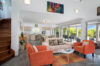 Bright open-plan living room with colorful armchairs, contemporary art, and garden views at a private villa in St Barts
