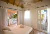 Cozy bedroom with soft natural light and balcony access overlooking the beach at a St Barts villa rental.