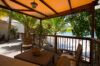 Shaded wooden terrace with lounge chairs overlooking the beach and palm trees at a St Barts villa rental.