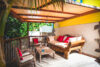 Covered terrace lounge with wooden furniture and red cushions at Villa Plumbago, st barts villa rental