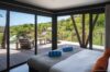 Bedroom with floor-to-ceiling windows opening to terrace and hillside view at Villa Plumbago, st barts villa rental