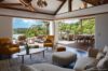 Open-plan living room with warm accents and ocean-view terrace at a private St Barts villa rental.