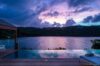 Sunset view from infinity pool of st barts villa overlooking calm lagoon and evening sky in soft lavender hues.