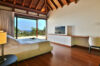 Bright ocean-view bedroom of st barts villa with vaulted wood ceiling, minimalist design, and private terrace access.