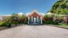 Elegant pink façade of st barts villa rentals surrounded by palm trees and tropical gardens.