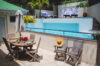 Poolside dining terrace with wooden table and tropical plants at vacation rental st barts.