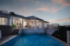 Evening view of illuminated infinity pool and terrace at st barts luxury villa overlooking the ocean.