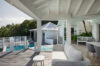 Elegant covered terrace with lounge and pool view at st barts villa rental surrounded by tropical greenery