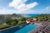 Infinity pool at luxury st barts villa with panoramic ocean view over lush island hills.