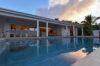 Evening view of illuminated terrace and pool reflecting sunset sky at a luxury villa rental in St Barts