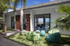 Garden terrace with palm trees and lounge seating outside modern villa rental in St Barthélemy.